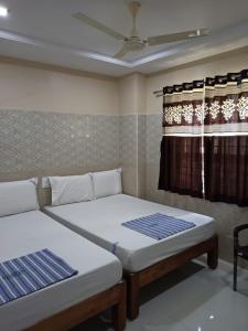 two beds in a room with a window at Vishnu Bhavan in Tirupati