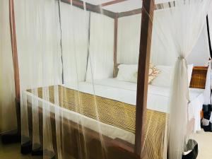 een slaapkamer met een hemelbed en witte gordijnen bij Sun Beach in Tangalle