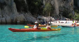 two people in kayaks in the water at a beach at La Petite Calanque in Marseille