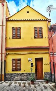 a yellow building with brown shutters on it at Casa vacanze Galena in Iglesias