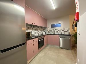 een keuken met roze kasten en een roestvrijstalen koelkast bij Myrtus - House with sea view and garden in Funchal