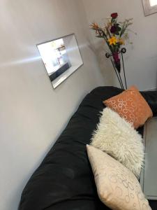 a black couch with pillows and a vase with flowers at MajaK Guesthouse in Soweto