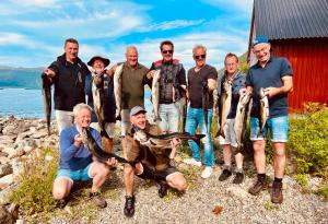 a group of people holding up their caught fish at Awesome Fishing, Boating and Nature Experience at Fiskesenter Birkeland in Rekdal