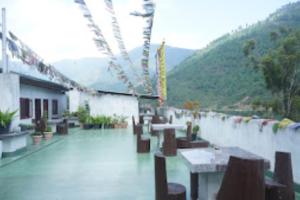 a building with tables and chairs and mountains in the background at The Mandala Hotel Dirang in Dirang Dzong
