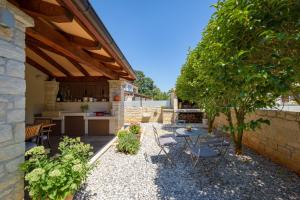 einen Garten mit einem Tisch und Stühlen sowie eine Küche in der Unterkunft Villa Clariss in Višnjan