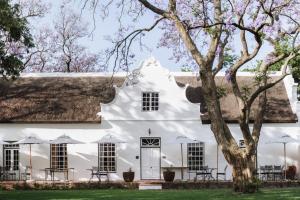 a white house with a thatched roof at Adara Palmiet Valley Luxurious Boutique Farm Hotel in Paarl
