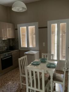 una cocina con una mesa blanca con sillas, una mesa blanca y un sillón en Smart stay Koridallos, en Pireo