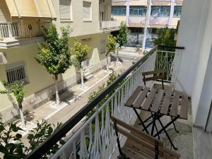 a balcony with a wooden table and bench on a street at Smart stay Koridallos in Piraeus