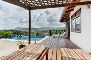 una terraza de madera con vistas a la piscina en Charming cottage located in Cap Estate - Orchid Cottage home, en Cap Estate