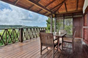 una terraza de madera con mesa y sillas. en Charming cottage located in Cap Estate - Orchid Cottage home, en Cap Estate