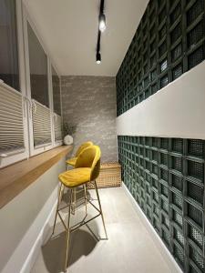 une chaise jaune dans une pièce avec un mur de bouteilles de vin dans l'établissement Apartament Augustiańska, à Cracovie
