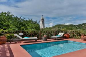una piscina con 2 tumbonas y una sombrilla en Villa Darcy - Serene 1 bedroom villa in Cap Estate with private pool villa, en Cap Estate