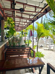 un banco de madera bajo una pérgola con mesas y sillas en Leisure Boutique Maafushi 维尼家 en Maafushi