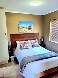 a bedroom with a large bed with a wooden headboard at Theescombe Accomodation in Port Elizabeth