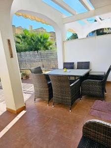 patio ze stołem i wiklinowymi krzesłami w obiekcie CASA DEl SOL PLAYA PUERTO BLANCO w mieście Calpe