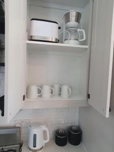 a kitchen with white cupboards with cups and appliances at The Lane Rodney Bay 1 bedroom rate - Newly renovated & tastefully furnished 3 bedroom house home in Rodney Bay Village