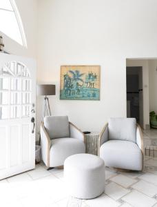 a living room with two chairs and a stool at The Date House - Four Bedroom Villa with Private Pool near the beach and Calabash Cove Resort villa in Bois dʼOrange