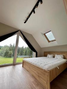 a bedroom with a large bed and a large window at Domek u Zająca in Krynica Zdrój
