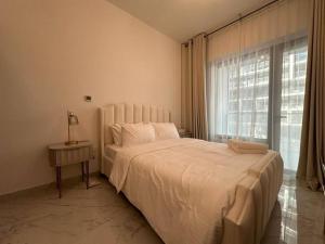 a white bedroom with a bed and a window at Layover in the Green City 203O3 in Al Qurayyah