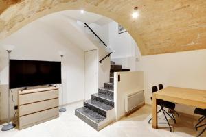 Habitación con escalera, TV y mesa. en Pick A Flat's Apartment in Place Vendôme/Tuileries - Rue Saint-Honoré, en París