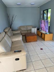 a living room with a couch and a flat screen tv at Arrival Lodge Hostel Accommodation in Gold Coast
