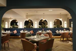 The Grand Plaza Hotel Smouha في الإسكندرية: غرفة طعام بها طاولات وكراسي وغرفة بها نوافذ