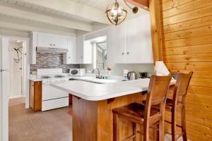 uma cozinha com armários brancos, um lavatório e cadeiras em 2349-Mountain Pines Cottage cabin em Big Bear City