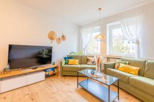 - un salon avec un canapé et une télévision dans l'établissement Stay Awesome - Urban Jungle Apartment Zentral, Wilhelmshöhe, à Cassel