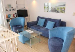 uma sala de estar com um sofá azul e duas cadeiras em Apartmentvermittlung Mehr als Meer - Objekt 7 em Niendorf