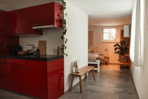 uma cozinha com armários vermelhos e um banco num quarto em Haus Meierhüsli em Malans