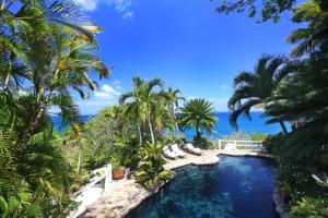 einen Pool in einem Resort mit Palmen in der Unterkunft Smuggler's Nest - Exotic & romantic villa villa in Cap Estate