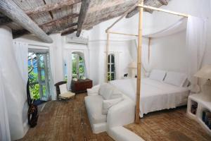 Habitación blanca con cama y sofá en Smuggler's Nest - Exotic & romantic villa villa, en Cap Estate
