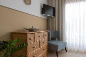 Habitación con vestidor, silla y TV. en Vila Camélia, en Oporto