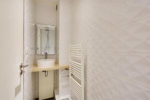 Baño blanco con lavabo y espejo en Pick A Flat's Apartments in Parc des Expositions - Rue Louis Vicat, en París