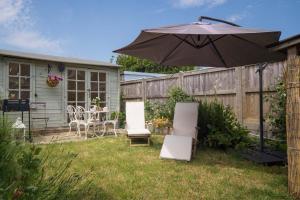 un patio con sombrilla, sillas y mesa en Fern Cottage, en Bembridge