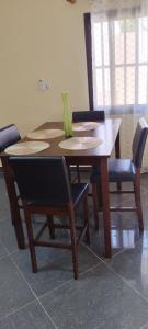 a wooden table with chairs and a green vase on it at ADISSA in Cotonou