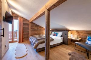 ein Schlafzimmer mit einem Bett in einem Zimmer mit Holzwänden in der Unterkunft PAPILL'ON - Boutique Hotel in La Tzoumaz