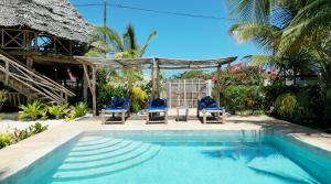 a pool with two chairs and a gazebo at Tofauti Inn in Makunduchi