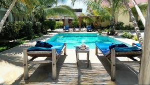 einen Pool mit zwei Stühlen und einem Tisch daneben in der Unterkunft Tofauti Inn in Makunduchi