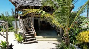 a small house with a thatched roof and a staircase at Tofauti Inn in Makunduchi