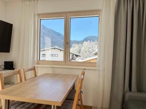 ein Esszimmer mit einem Tisch und einem großen Fenster in der Unterkunft Apartments ALPsmart in Oetz