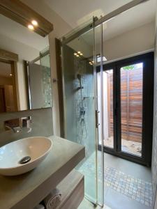 La salle de bains est pourvue d'un lavabo et d'une douche en verre. dans l'établissement VILLA LILOU, Splendide villa au centre de Grand Baie, à Grand Baie