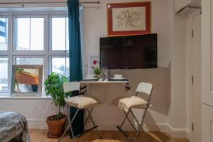 a room with a desk with two chairs and a tv at Amazing Finsbury Park Studio in London