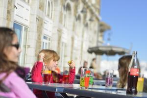 a little girl sitting at a table with drinks at Villages Clubs du Soleil - SUPERBAGNERES in Superbagnères