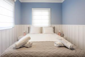 Un dormitorio con una cama blanca con paredes y ventanas azules en Appartements BnBIsrael - Hovevei Tsiyon Jasmin, en Tel Aviv