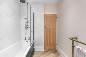 a bathroom with a bath tub and a shower at OnSiteStays New Large modern 4 bed, Parking, Wifi, 2 x Bathroom in Orpington +27 photos