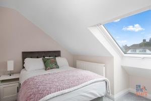 um quarto com uma cama e uma grande janela em OnSiteStays New Large modern 4 bed, Parking, Wifi, 2 x Bathroom em Orpington
