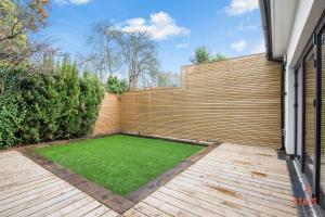 um quintal com uma cerca de madeira e um relvado verde em OnSiteStays New Large modern 4 bed, Parking, Wifi, 2 x Bathroom em Orpington