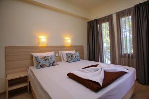 a bedroom with a large white bed with two windows at Aktaion Guest Rooms in Skopelos Town