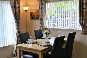a dining room table and chairs with a table and a window at Bluebell Lodge in Morpeth